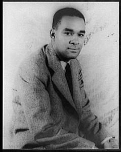 Richard Wright, a Black man, seated wearing a suit and tie, stares into the camera