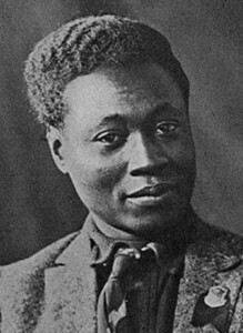 Claude McKay, a Black man, wears a suit and looks into camera.